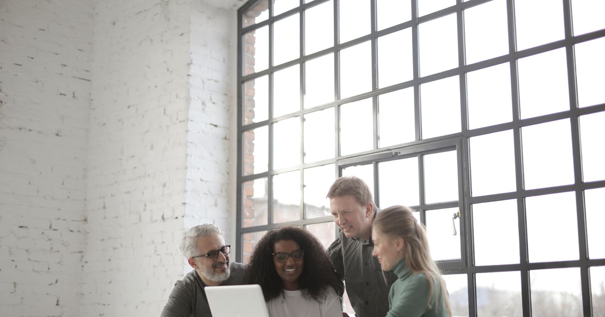 team discussing a website launch plan around one laptop