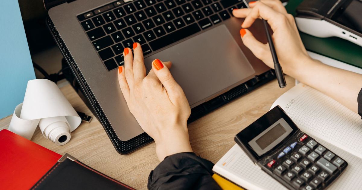 hands typing invoice data into a laptop next to a calculator and a notebook, the manual entry that automation removes