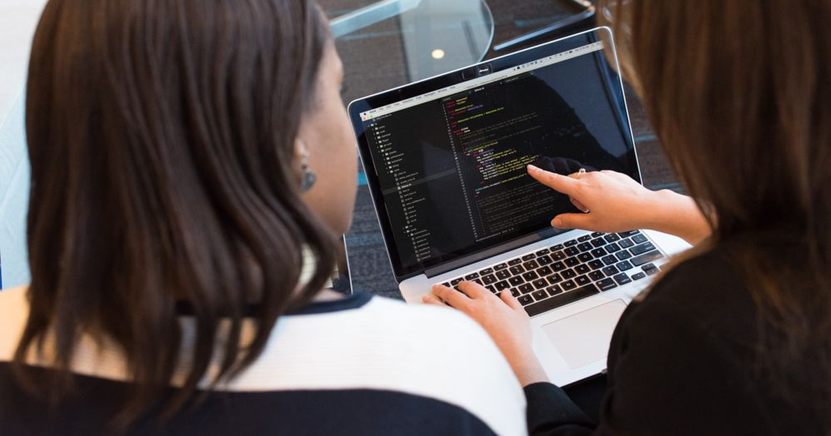 два разработчика проверяют исходный код на ноутбуке при технической оценке подрядчика