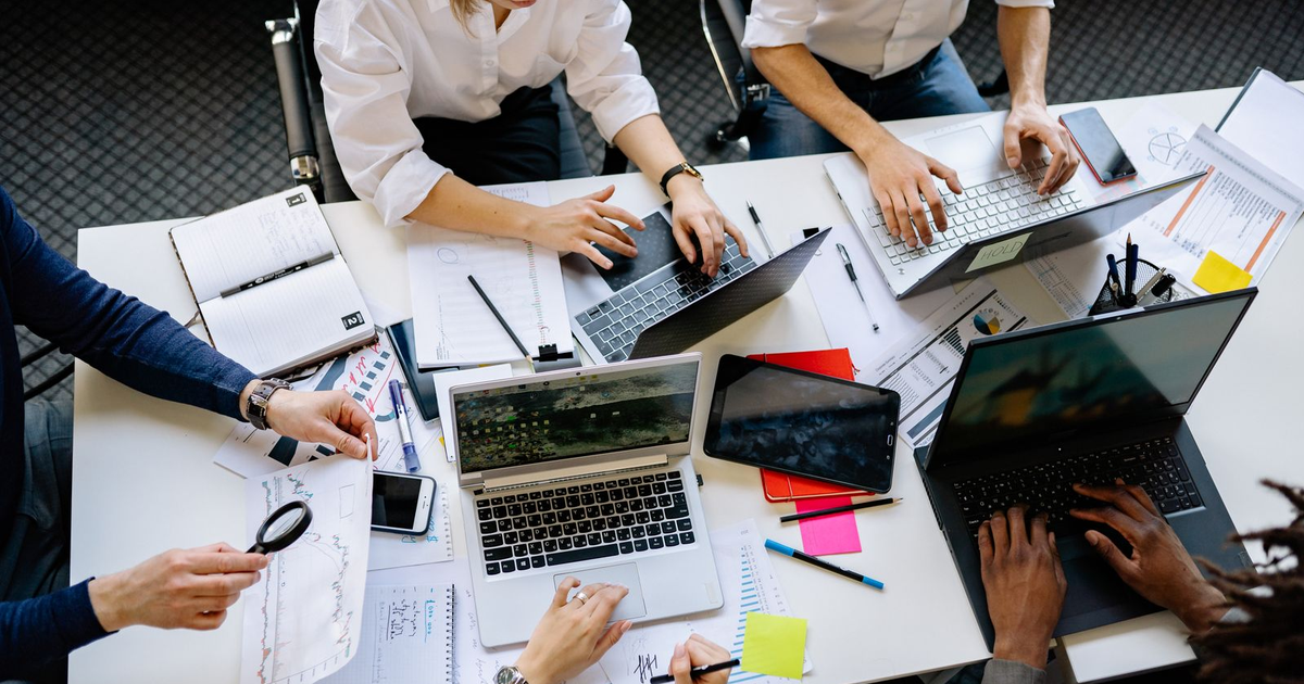 equipo de proyecto planificando las fases del desarrollo de una página web para empresa ante portátiles